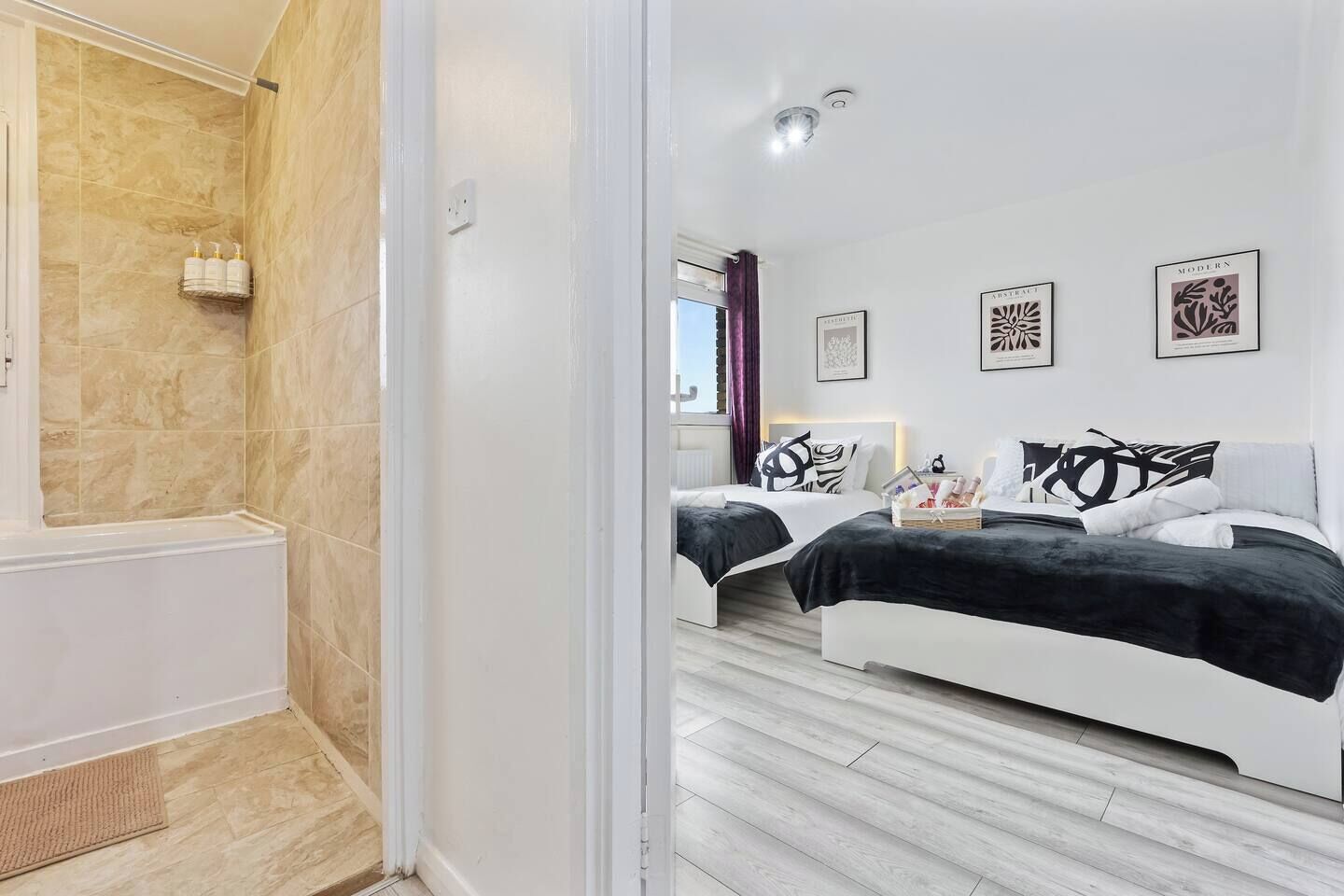 Une chambre d’hôtel moderne dotée d’une douche, de deux lits et d’œuvres d’art accrochées aux murs.