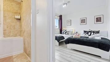 Une chambre d’hôtel moderne dotée d’une douche, de deux lits et d’œuvres d’art accrochées aux murs.