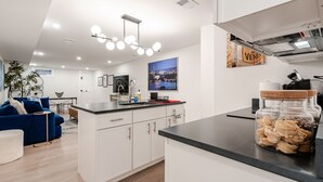 Een moderne keuken met witte kasten, een zwart aanrecht en een hangende lamp.