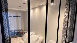 A modern hotel room with a bed, a desk with a chair, a sink, and a window with blinds. - Standing apartment, heart of Bareges village, close to amenities, sleeps 1 to 8 (Barèges)