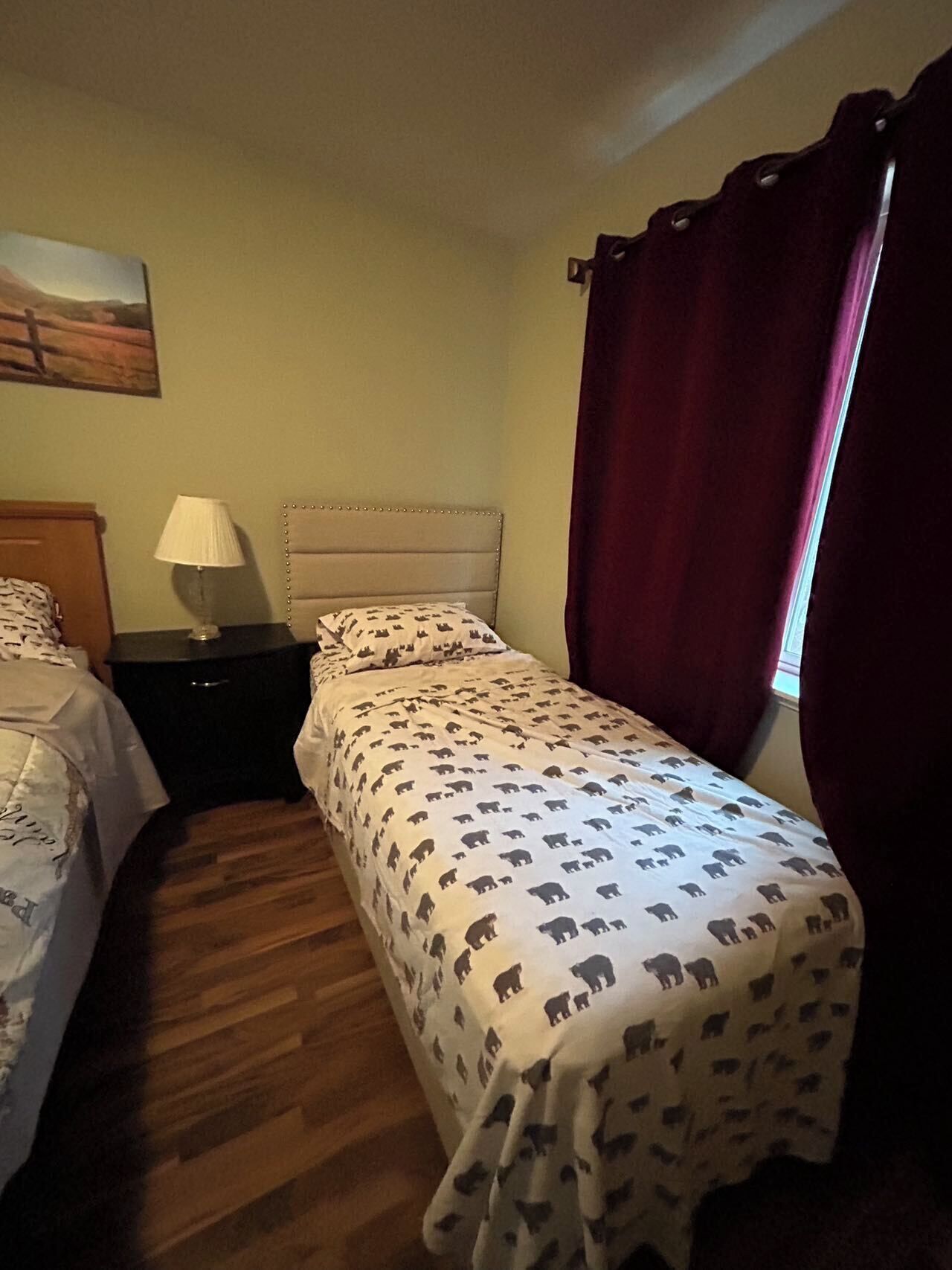 Une chambre avec deux lits, une table de chevet, une lampe et un tableau au mur.