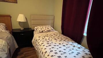 Une chambre avec deux lits, une table de chevet, une lampe et un tableau au mur.