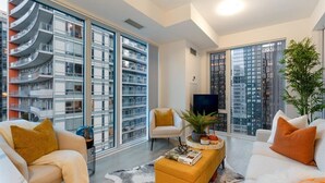 Una sala de estar moderna con ventanas amplias, un televisor de pantalla plana y un conjunto de sofás.