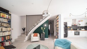 Un salon moderne avec un escalier, un coin repas et une cuisine.