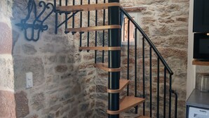 Una escalera de caracol con escalones de madera y barandillas de metal negro, que conduce a un piso superior.