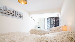 Habitación de hotel con dos camas, un adorno en la pared, una lámpara y vistas al exterior.