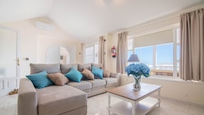 Una sala de estar moderna con un sofá color beige, una mesa de centro de madera y un jarrón con flores.