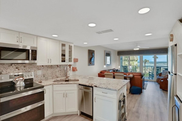 Una cocina moderna con muebles blancos, microondas integrado y estufa.