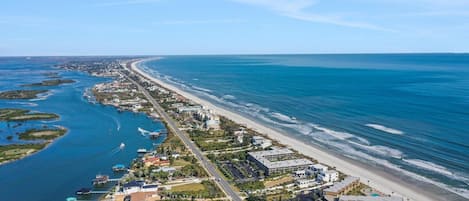 An aerial view of a coastal area with a beach, marina, and buildings.