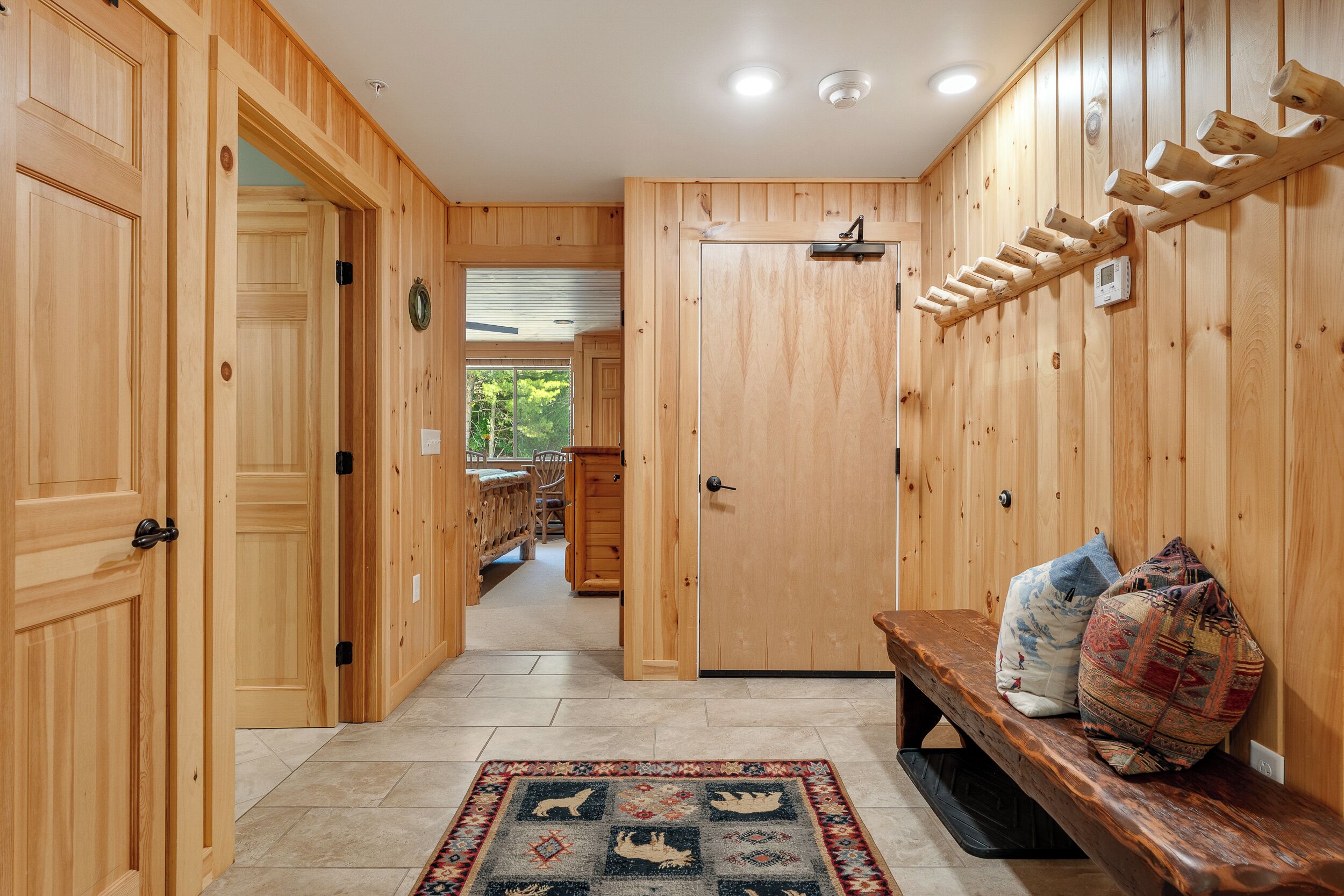 A wooden interior with a bench, a rug, and a wall-mounted rack.