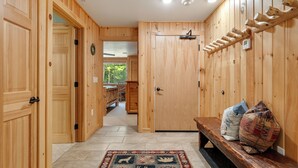 Un intérieur en bois avec un banc, un tapis et une étagère fixée au mur.