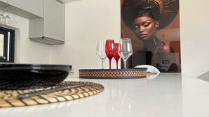 A modern kitchen with a white countertop, a woven serving tray, and two wine glasses. - Apartment with swimming pool and magnificent view of Tarrafal Bay (Tarrafal)
