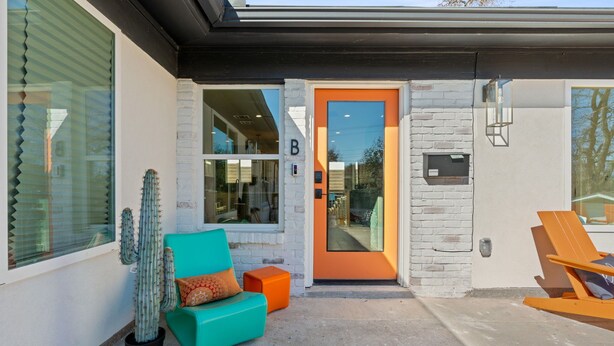 A modern building with a bright orange door, a teal sofa, a cactus, and a wooden chair outside. - Walk S Congress Pool Putt Putt 3 KING/2 BATH FULLY Remodeled (Austin)