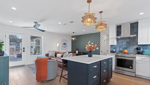 A modern kitchen with a central island, white cabinets, and a backsplash with a geometric pattern. - Walk S Congress Pool Putt Putt 3 KING/2 BATH FULLY Remodeled (Austin)