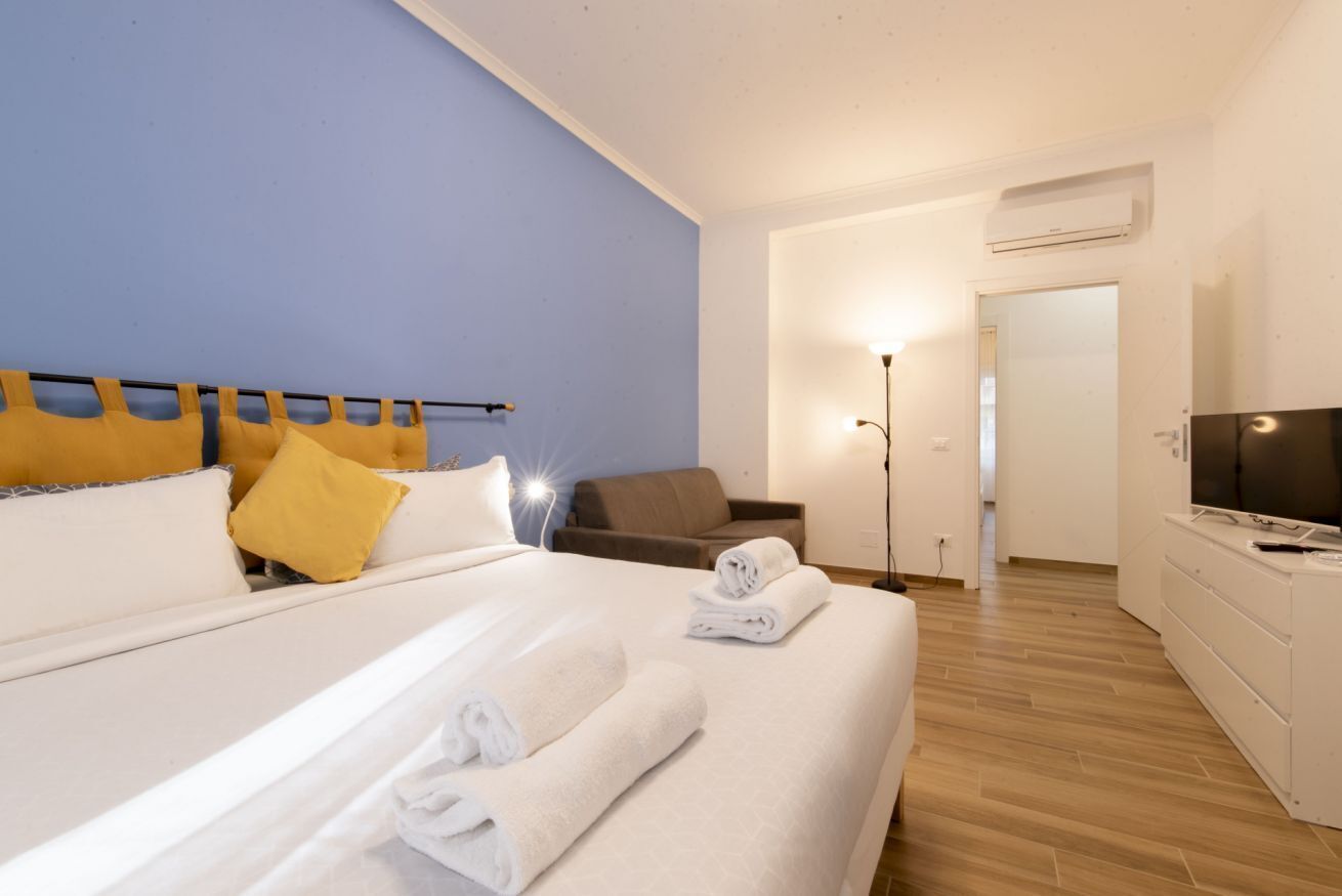 Hotelkamer met een bed, bureau, stoel, televisie en een airconditioner.