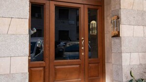 Puerta doble de madera con paneles de vidrio, incrustada en una pared de piedra.