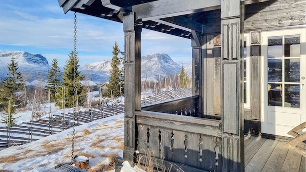 Une cabane en bois dotée d’un balcon donnant sur un paysage montagneux enneigé.