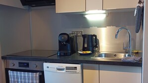 Una cocina compacta equipada con microondas, cafetera, lavavajillas y pileta.