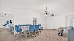 Un salón amplio con una mesa de comedor, sillas, un sofá y un televisor.