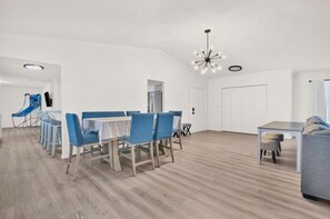 Un salón amplio con una mesa de comedor, sillas, un sofá y un televisor.
