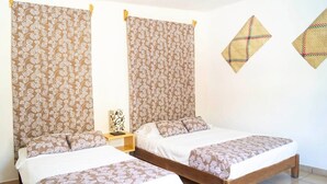 Ein Doppelzimmer mit zwei Betten, einem Nachttisch und einem Wandregal.