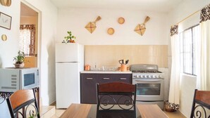 Eine kompakte Küche mit Kühlschrank, Herd, Mikrowelle und einem Essbereich mit Tisch und Stühlen.