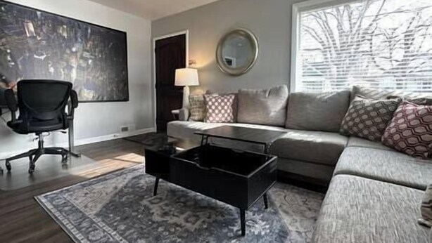 A modern living room with a grey sofa, a black coffee table, and a patterned rug.
