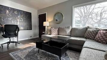 A modern living room with a grey sofa, a black coffee table, and a patterned rug.