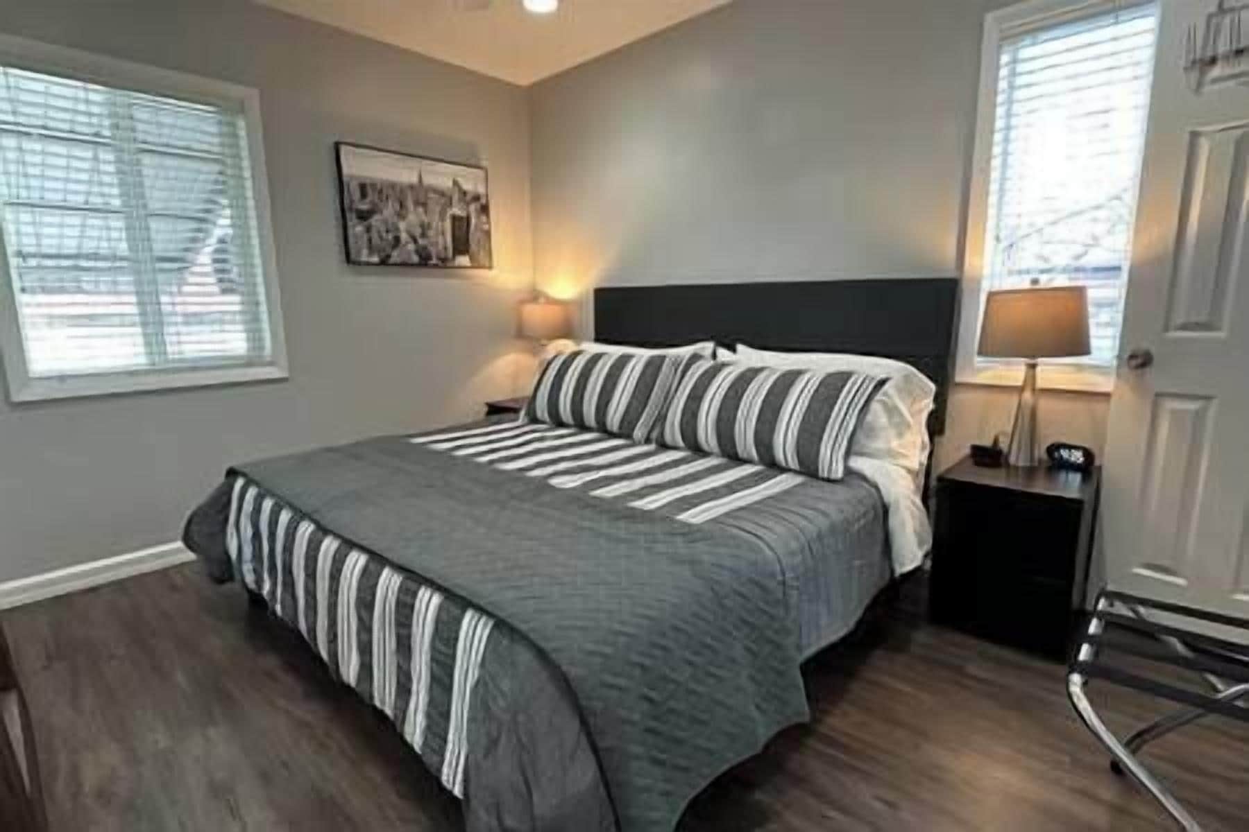 A bedroom with a large bed, a nightstand, a lamp, and a picture on the wall.