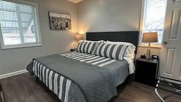 A bedroom with a large bed, a nightstand, a lamp, and a picture on the wall.