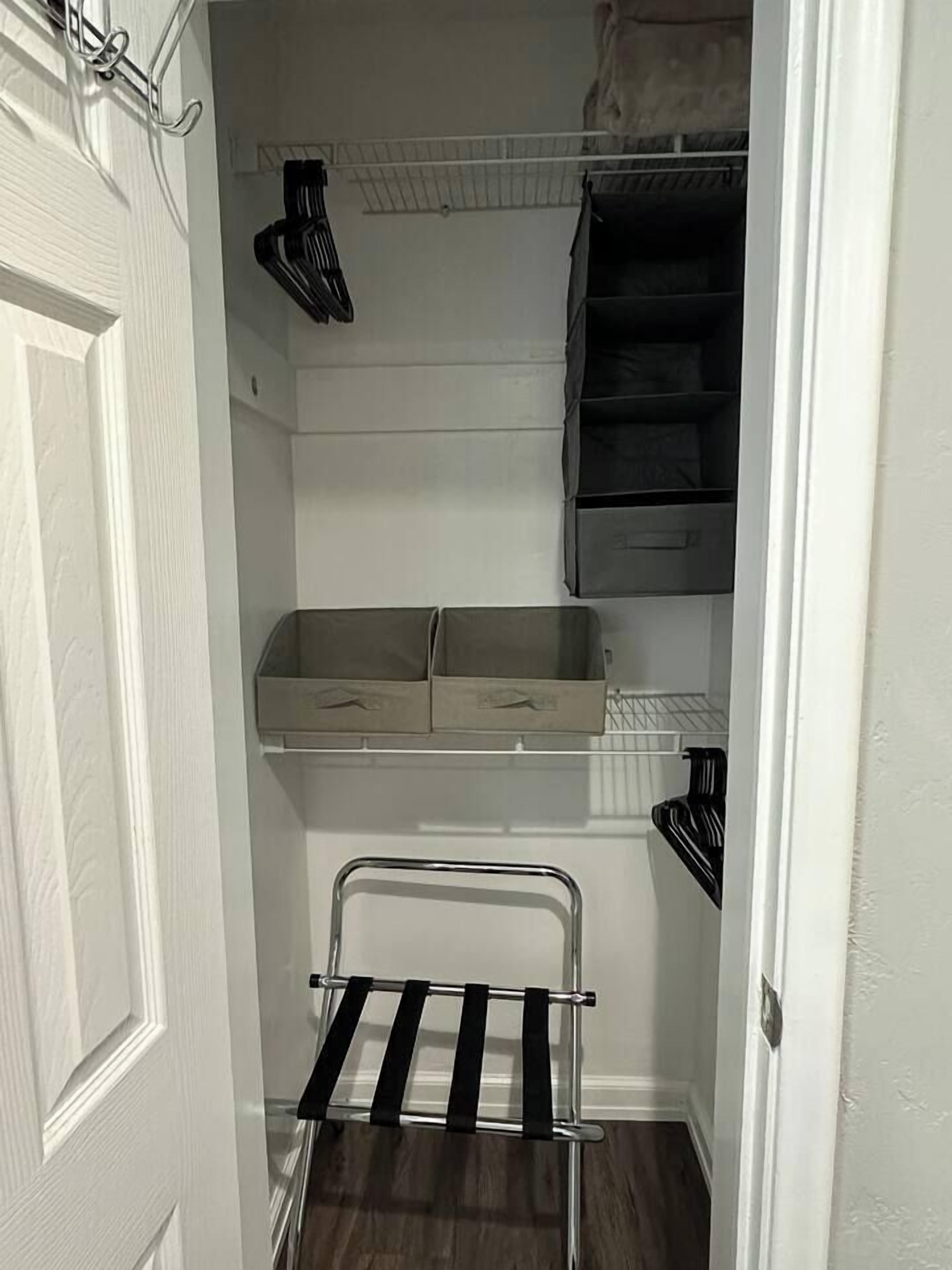 A narrow hallway with a metal rack, two open storage boxes, and a black appliance.