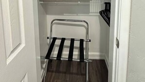 A narrow hallway with a metal rack, two open storage boxes, and a black appliance.