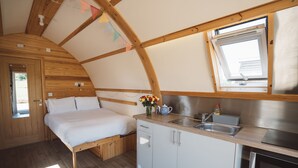 Una habitación compacta con cama, kitchenette pequeño y ventana.