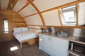 Une chambre compacte comprenant un lit, une petite kitchenette et une fenêtre.