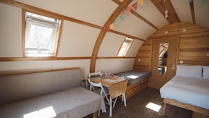 Una stanza accogliente e compatta con soffitto in legno, un letto, una panca e un tavolino.