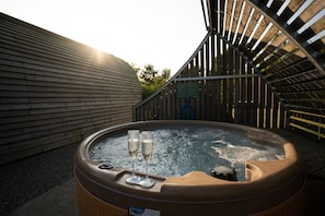 Un jacuzzi con dos copas de champán, rodeado de paredes de madera y una escalera metálica.