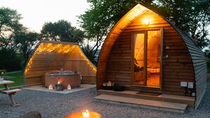 Una cabaña acogedora de madera con jacuzzi, una fogata y un comedor.