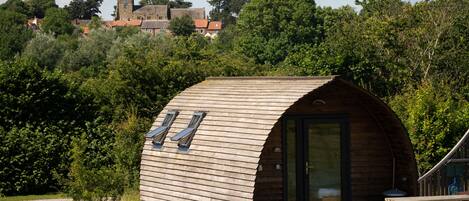 Une cabane en bois avec un toit incurvé, une petite véranda et une table de pique-nique.