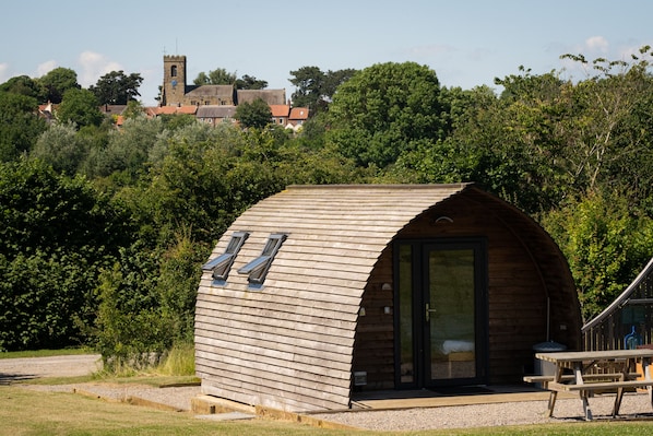 A wooden cabin with a curved roof, a small porch, and a picnic table. - Cosy Cabin with Hot Tub in North Yorkshire (Northallerton)