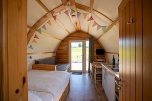 A cozy, wooden interior with a bed, a small kitchenette, and a view of the outdoors. - Cosy Cabin with Hot Tub in North Yorkshire (Northallerton)