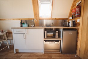 Een kleine keuken met een vaatwasser, magnetron en koelkast.
