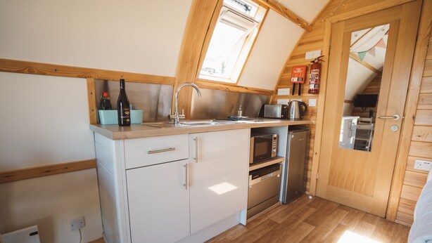 Une cuisine compacte dotée d’un plan de travail en bois, d’un évier, d’un four à micro-ondes et d’un lave-vaisselle.