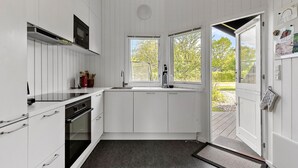 Una cocina moderna con armarios blancos, horno integrado, lavamanos y ventana con vistas al exterior.