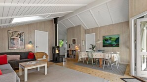 Una sala de estar acogedora con sofá, mesa de centro y chimenea. Hay un comedor con mesa y sillas.