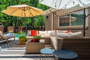 A patio area with wicker furniture, a pool, and a large umbrella. - Pool House w/ Outdoor Bar, Game Room & Movie Room (Irving)