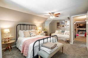 A bedroom with two beds, a ceiling fan, and a small table with a lamp.