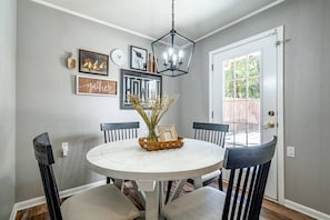 A dining area with a round table, black chairs, and a chandelier.
