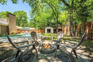 A backyard with a fire pit, outdoor seating, and a swimming pool. - Pool House w/ Outdoor Bar, Game Room & Movie Room (Irving)