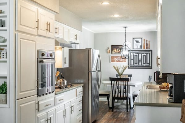 A modern kitchen with white cabinetry, stainless steel appliances, and a central island.