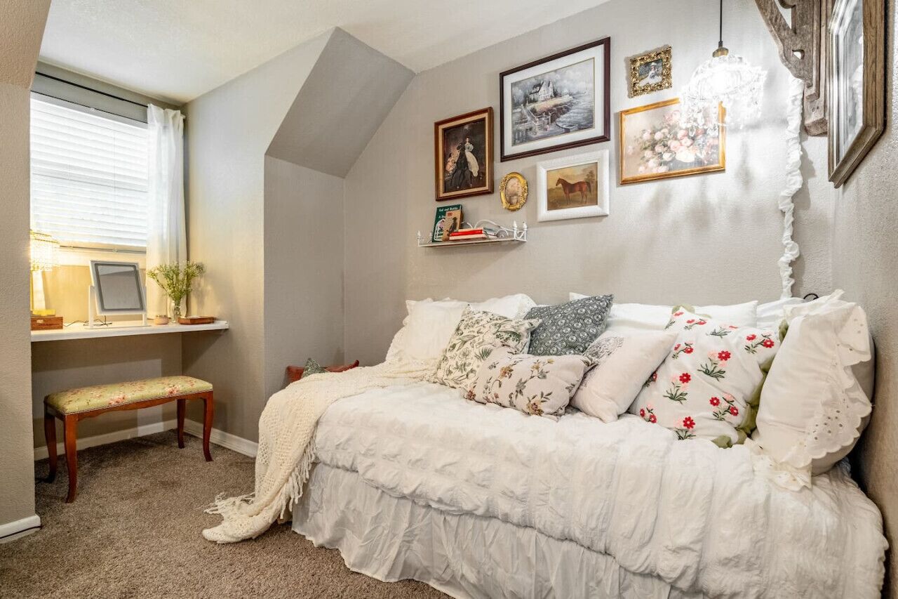 A cozy bedroom with a bed, a desk with a chair, and a window with curtains.